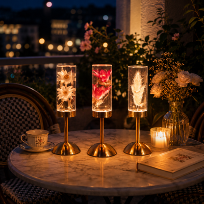 Ensemble Little Daisy avec lampes décoratives Marguerite, Lotus Rose et Plume sur une table bistro extérieure, créant une ambiance douce et élégante au coucher du soleil.