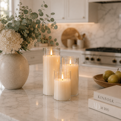 Ensemble de 3 bougies LED rechargeables en verre transparent posé sur un îlot de cuisine en marbre dans une cuisine haut de gamme au style premium. Ces bougies décoratives sans flamme diffusent un effet flamme réaliste et créent une ambiance chaleureuse, élégante et apaisante, parfaite pour la cuisine, la salle à manger ou la décoration intérieure contemporaine.