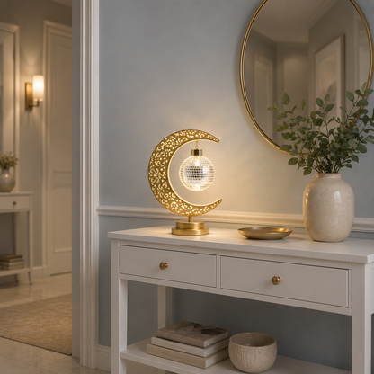 Lampe Lune Enchantée Boule Miroir dorée allumée sur une console blanche dans un hall d'entrée élégant, éclairage LED décoratif créant une ambiance chaleureuse et raffinée.