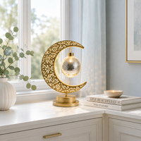 Lampe Lune Enchantée Boule Miroir dorée allumée sur une console blanche près d'une fenêtre, éclairage LED décoratif créant une ambiance douce et chaleureuse dans un intérieur élégant.