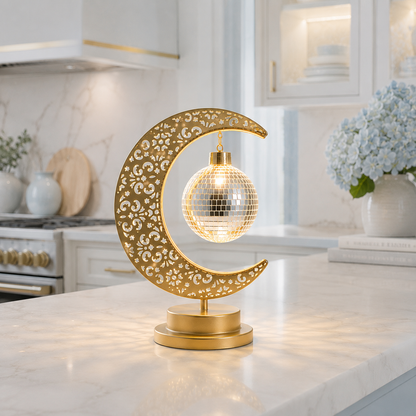 Lampe Lune Enchantée Boule Miroir dorée allumée sur un comptoir de cuisine moderne, éclairage LED décoratif créant une ambiance chaleureuse, élégante et raffinée.