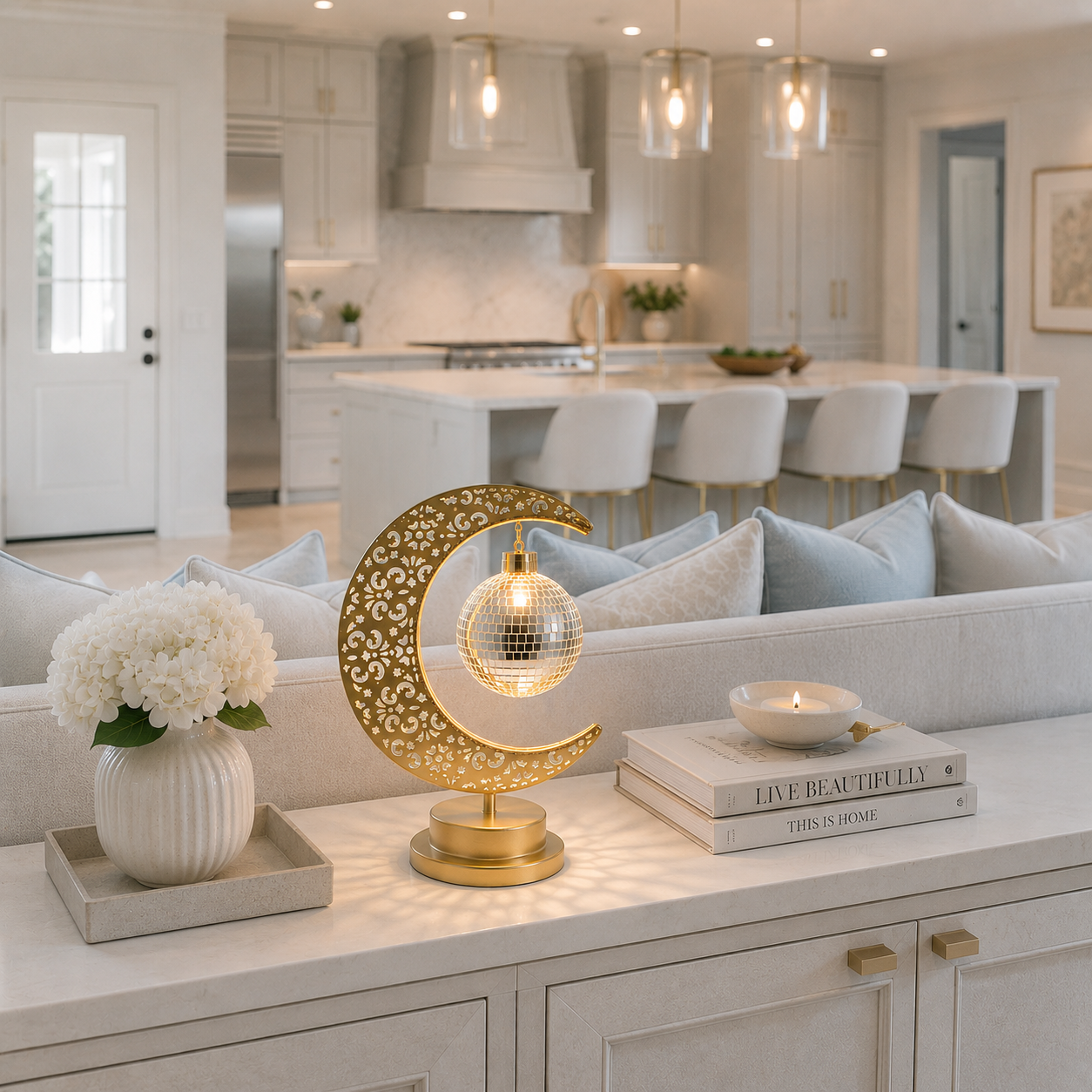 Lampe Lune Enchantée Boule Miroir dorée allumée sur une console derrière un canapé avec vue sur une cuisine moderne, éclairage LED décoratif créant une ambiance chaleureuse, élégante et raffinée.