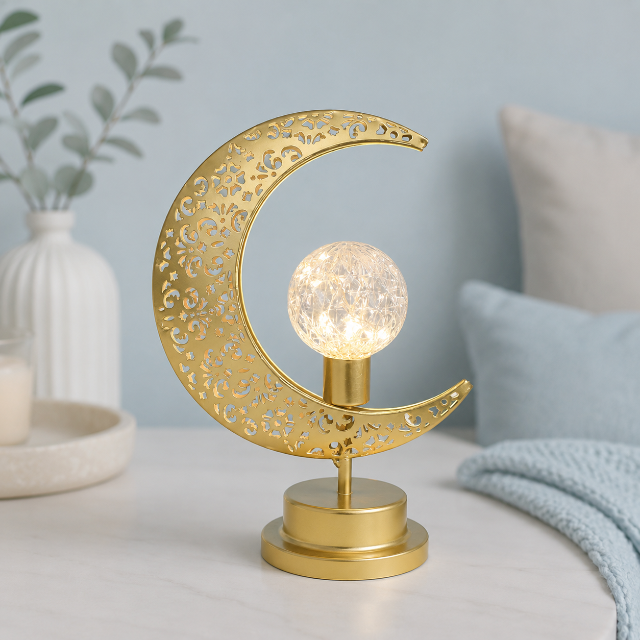 Lampe Lune Enchantée Boule Cristal dorée allumée avec boule lumineuse texturée, éclairage LED décoratif sur fond greige bleu poudre, idéale pour le salon, la chambre ou le bureau.