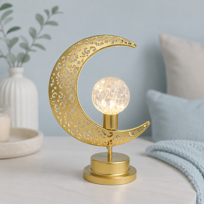 Lampe Lune Enchantée Boule Cristal dorée allumée avec boule lumineuse texturée, éclairage LED décoratif sur fond greige bleu poudre, idéale pour le salon, la chambre ou le bureau.