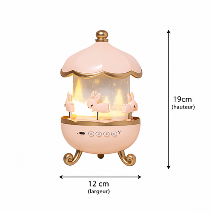 Veilleuse projecteur carrousel rose avec lapins décoratifs, lumière chaleureuse et dimensions illustrées de 19 cm de hauteur par 12 cm de largeur sur fond blanc.